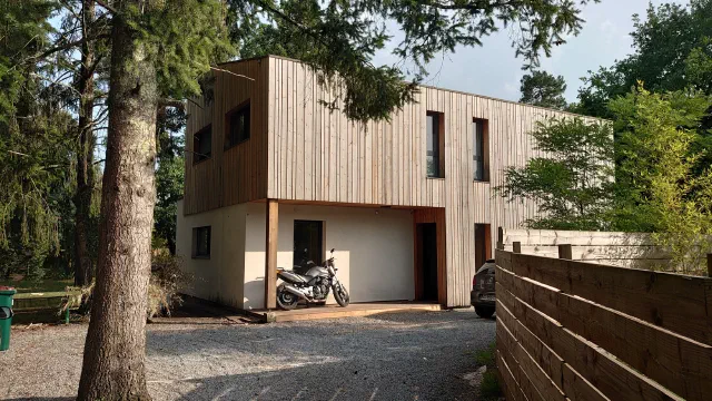 Maison contemporaine bardée de bois dans un jardin arboré